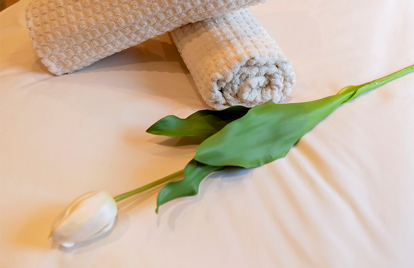 A white tulip and towels on a spa treatment bed